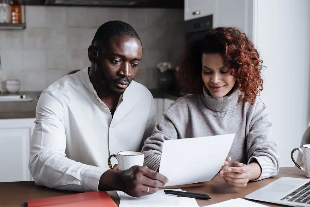 Couple comparing car loan refinance savings at home in Canada