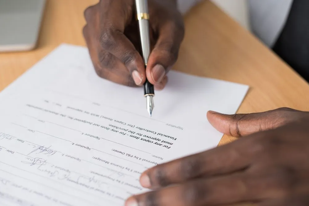 Signing paperwork to refinance your car loan in Canada