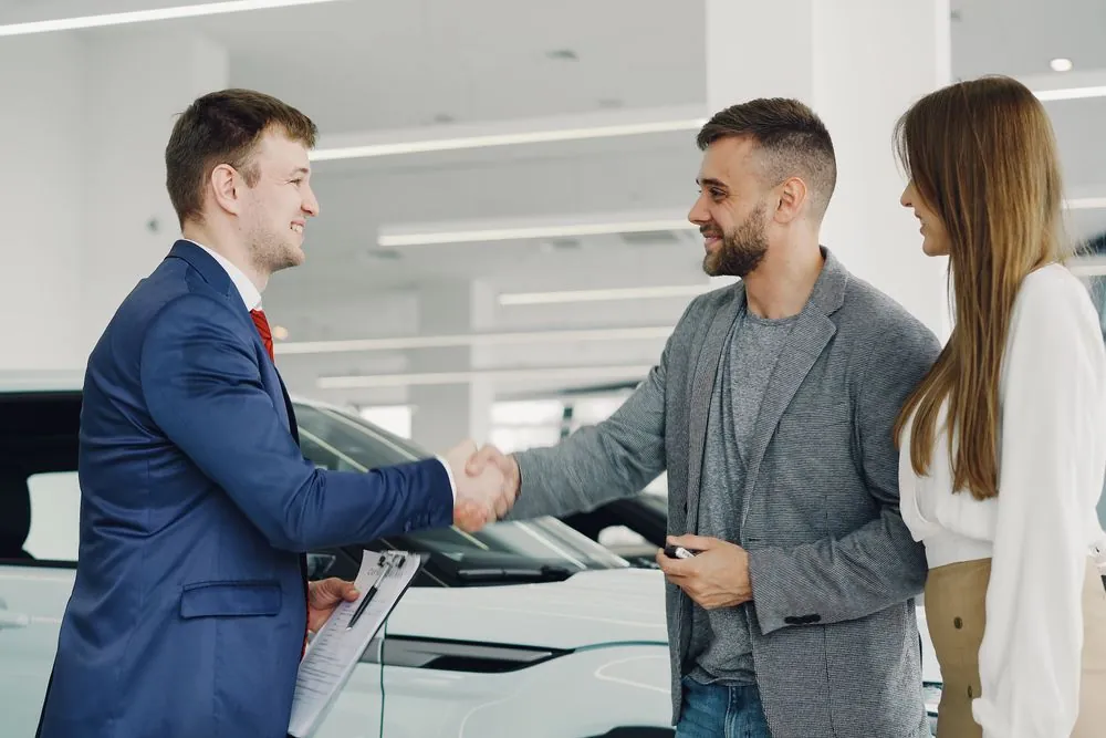 Couple getting approved for a car loan shaking hands with a dealer in Canada