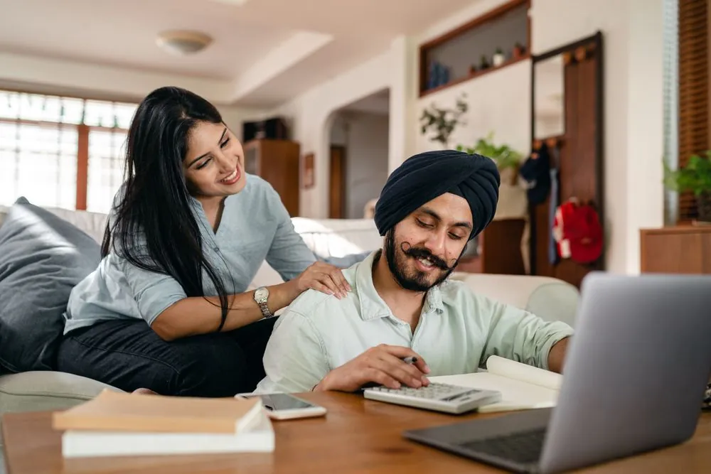 Couple comparing refinance auto loan offers on a laptop in Canada