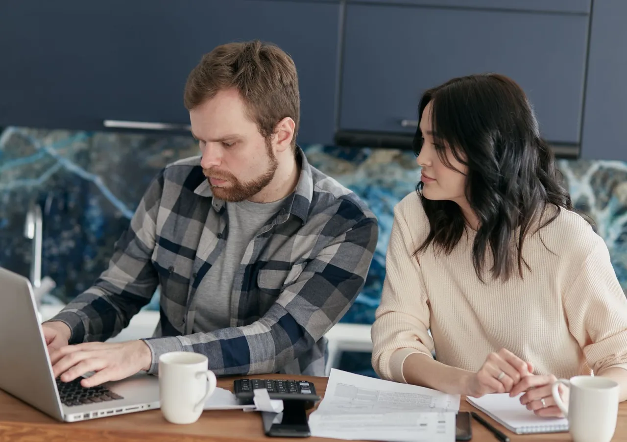 Couple comparing bank, dealership, and credit union car financing offers at home