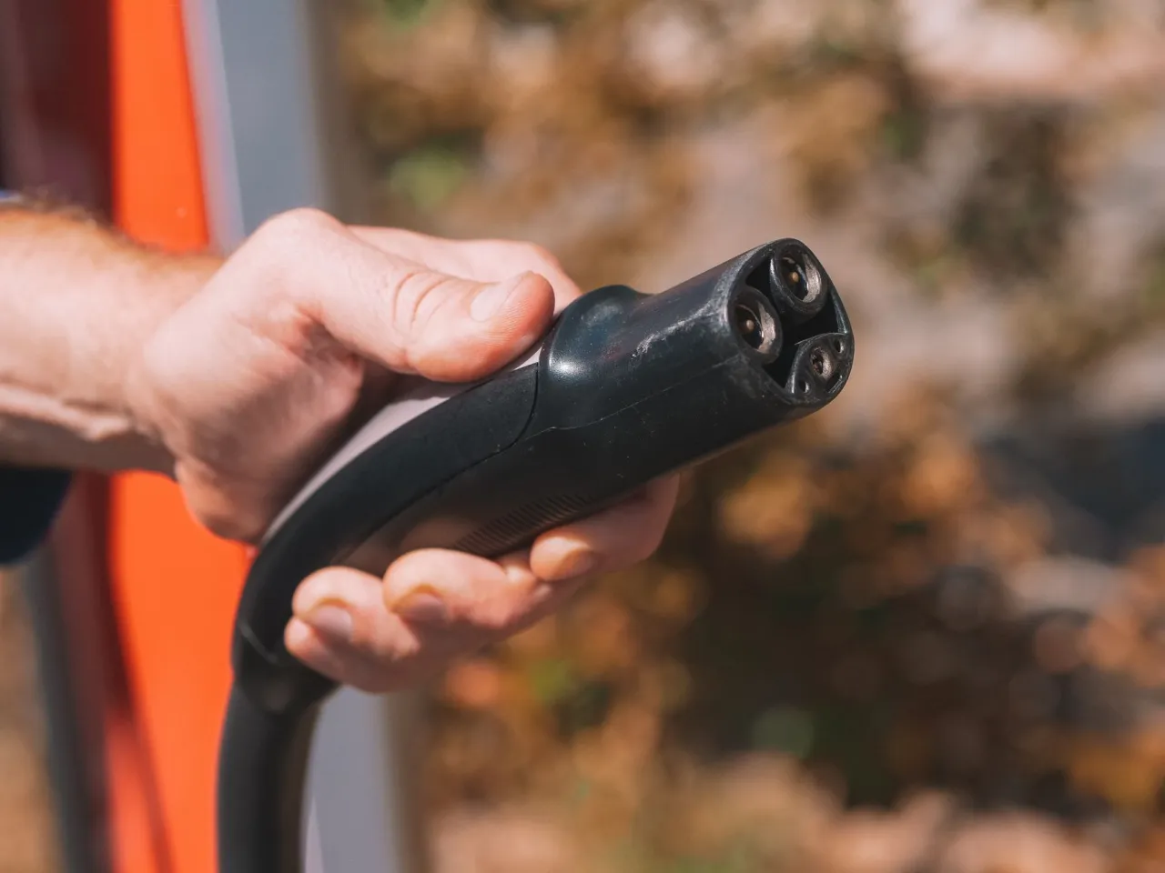 Close-up of an electric vehicle fast-charging plug before connecting