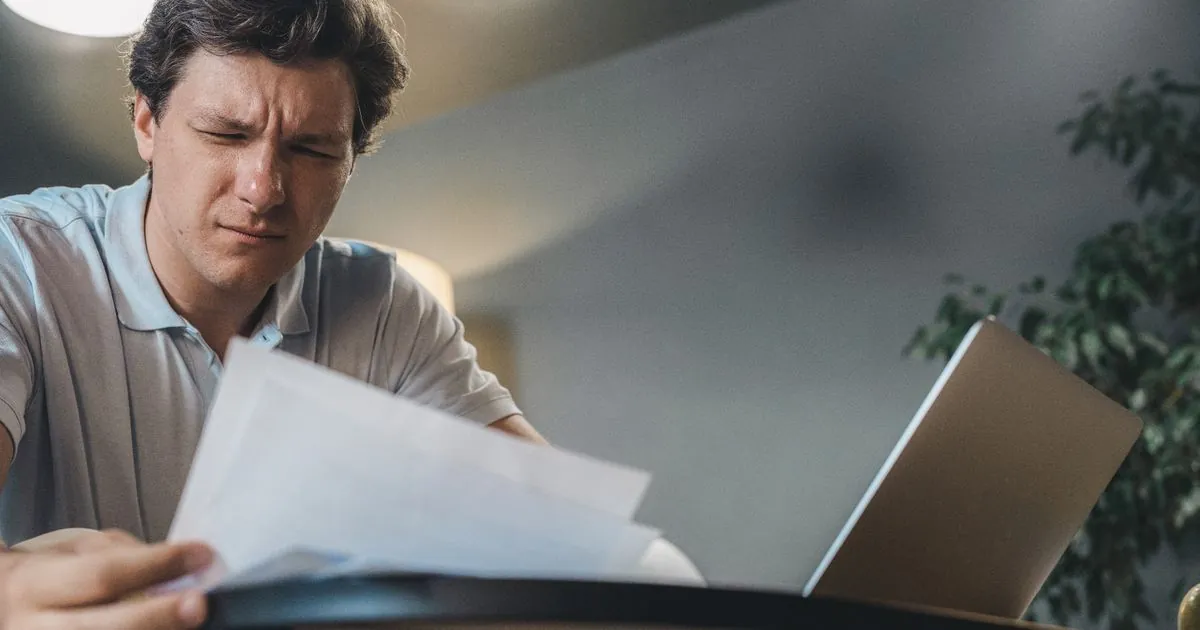 Driver working out how to get out of a car loan in Canada with payout statement and laptop