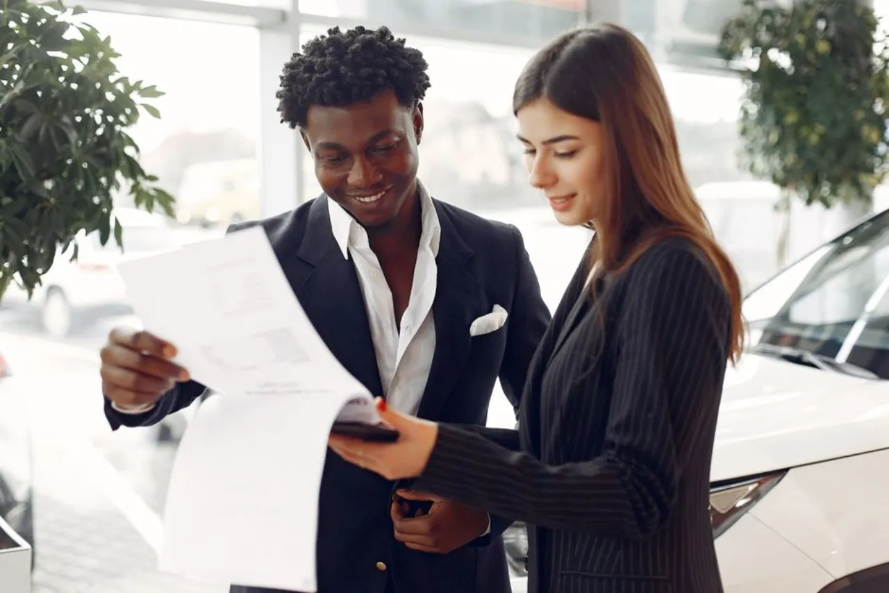 Reading a rent to own car contract carefully before signing at a dealership