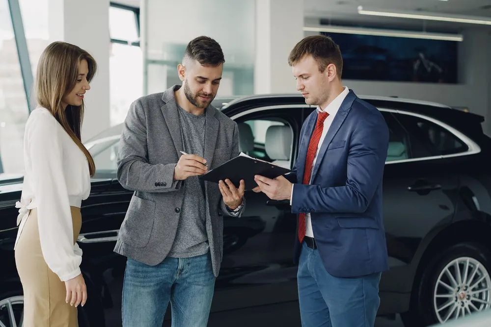 Comparing bad credit car loans routes, reviewing offers at a dealership finance desk