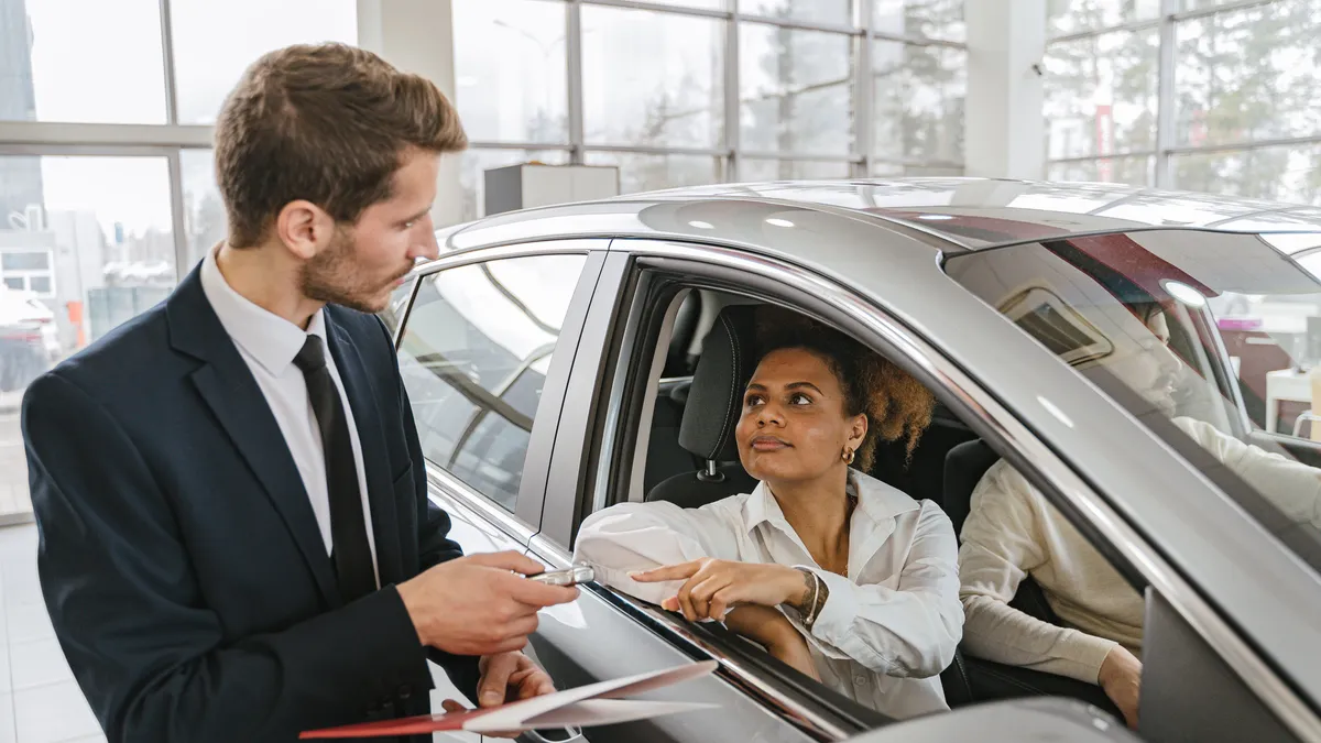 Bad credit car loans Canada: dealer handing the keys to a buyer seated in her approved vehicle